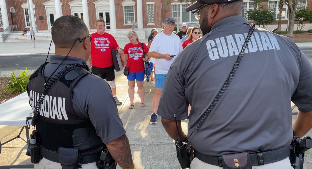 Armed guards use security wands on fans as they enter the stadium at Manatee High School ahead of Friday night's game. (Spectrum News/Nick Popham)