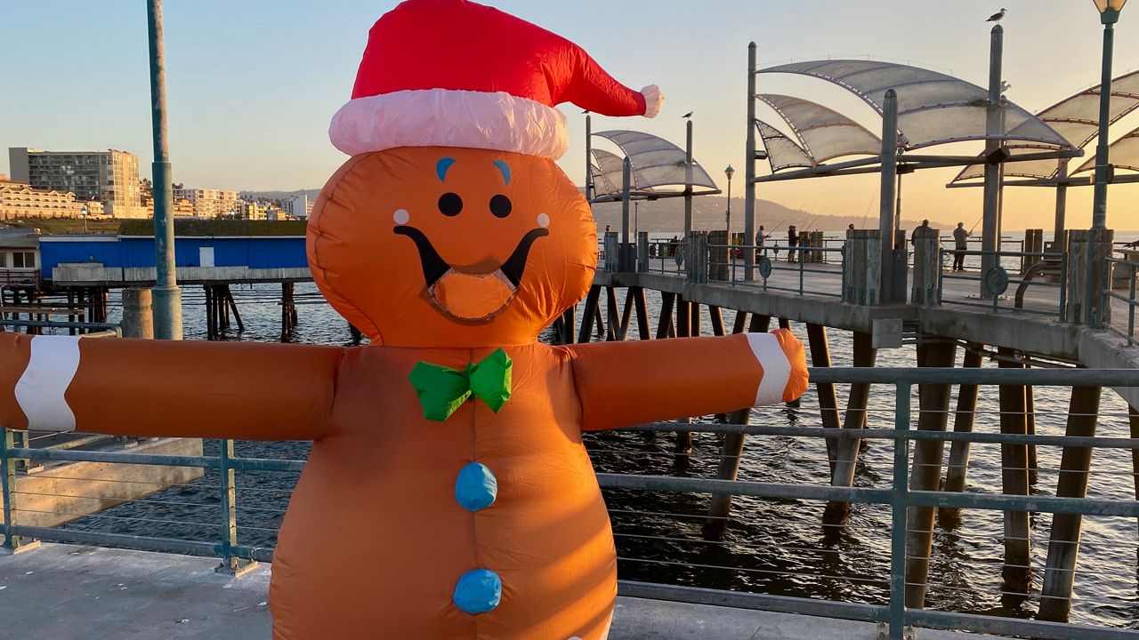 The Redondo Rex, clad in an inflatable gingerbread man costume, poses at the Redondo Pier. (Spectrum News/David Mendez)