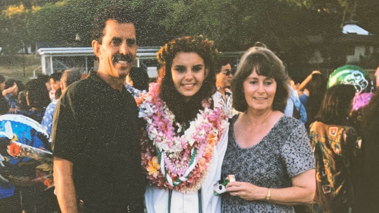 Jessica Machado is draped with lei at her graduation from Mid-Pacific Institute in 1995, while her parents stand on either side of her. (Photo courtesy of Jessica Machado)