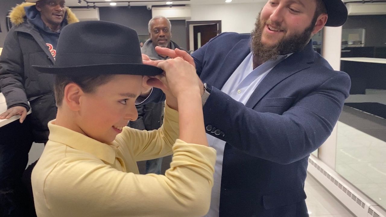 A man putting a hat on a child at Bellissimo Hats