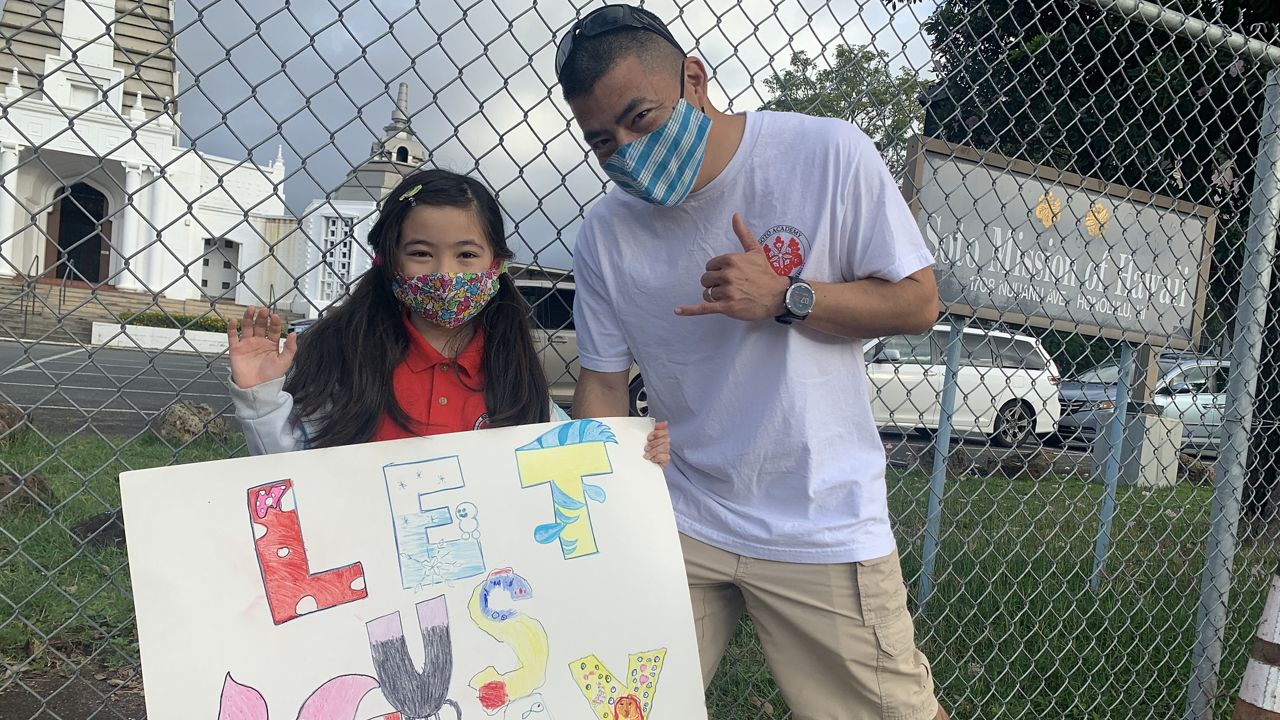 A parent and student attend a sign-waving event in front of Soto Mission. (Photo courtesy of Andrea Deutsch)