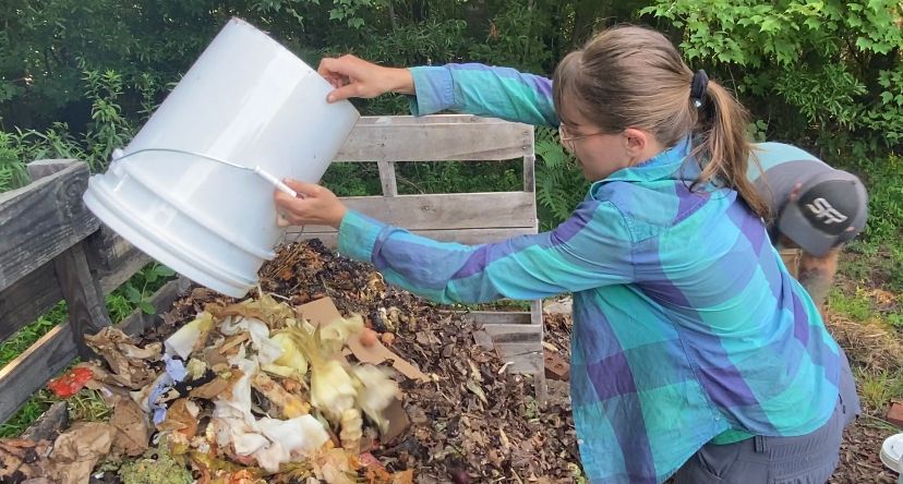 Brittany Peters and Richard Raggi pour compost items in pile.
