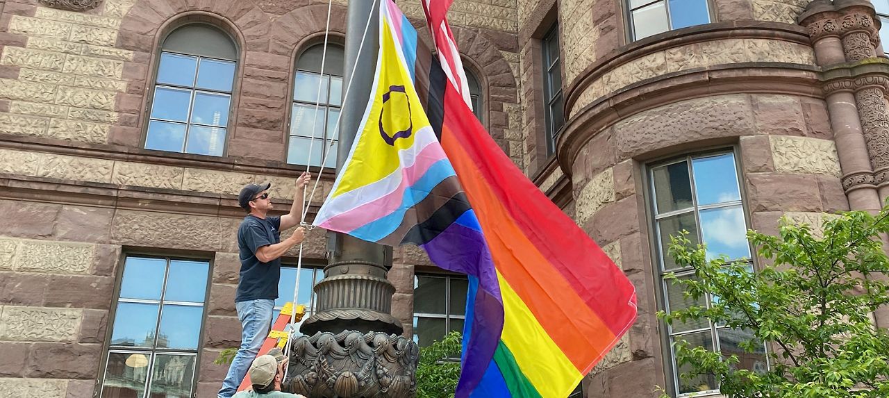 A City of Cincinnati employee raises the Pride flag at City Hall. The flag was donated by city employees. (Casey Weldon/Spectrum News 1)