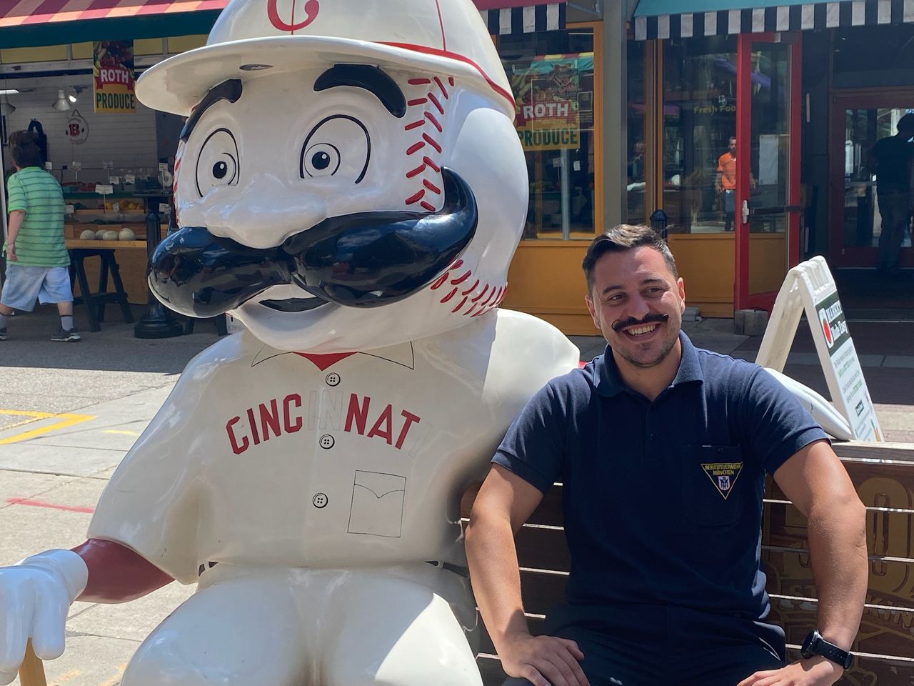 Philip Knecht, of Munich, Germany, poses with a Cincinnati Reds statue at Findlay Market in Cincinnati, Ohio.