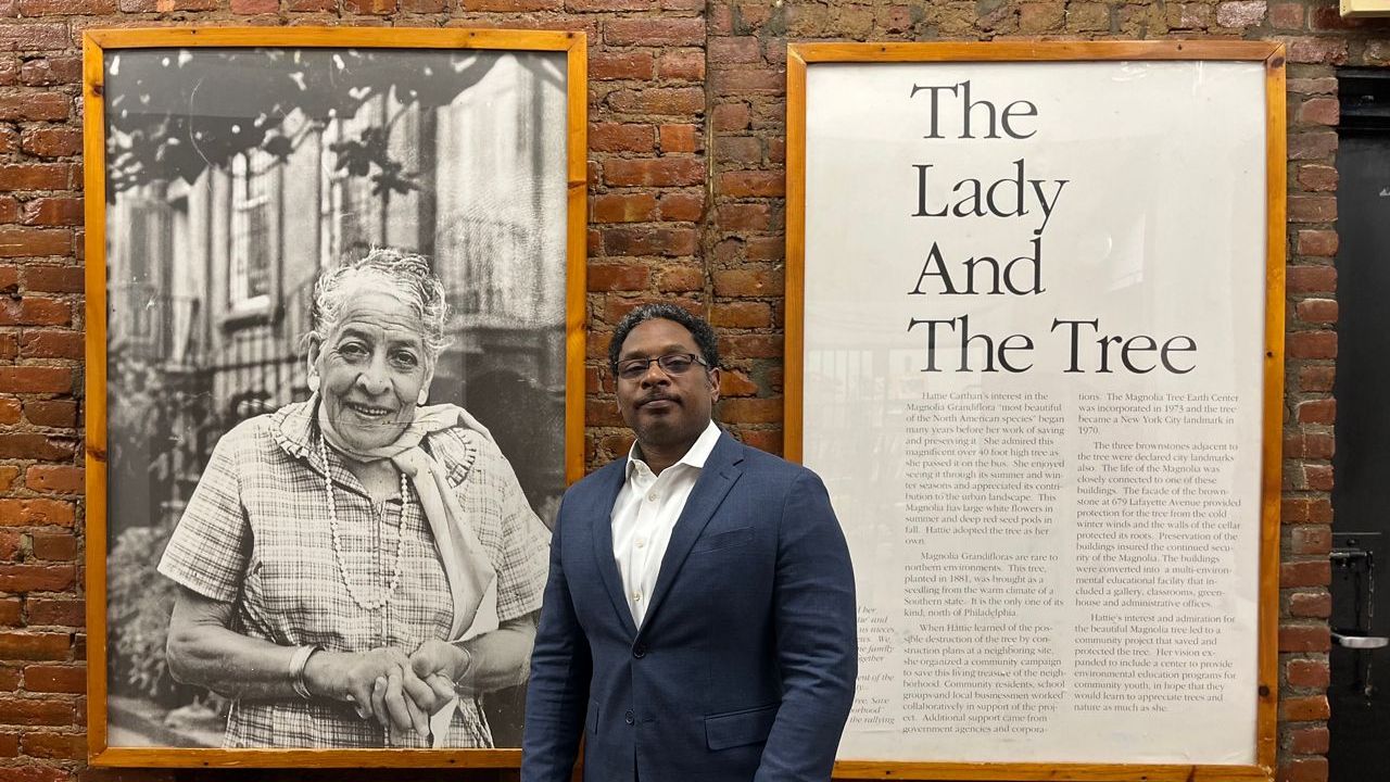 Wayne Devonish, the chair of the Magnolia Tree Earth Center's board, stands in front of a photograph of Hattie Carthan, the center's founder, that hangs on a wall inside the center. (NY1/Ari Ephraim Feldman)