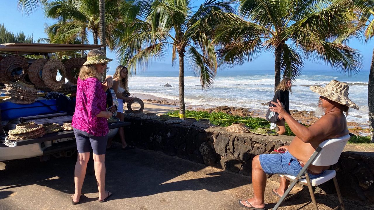 A man sells papale along Kamehameha Highway to people on the way to see the Eddie. (Spectrum News/Michelle Broder Van Dyke)