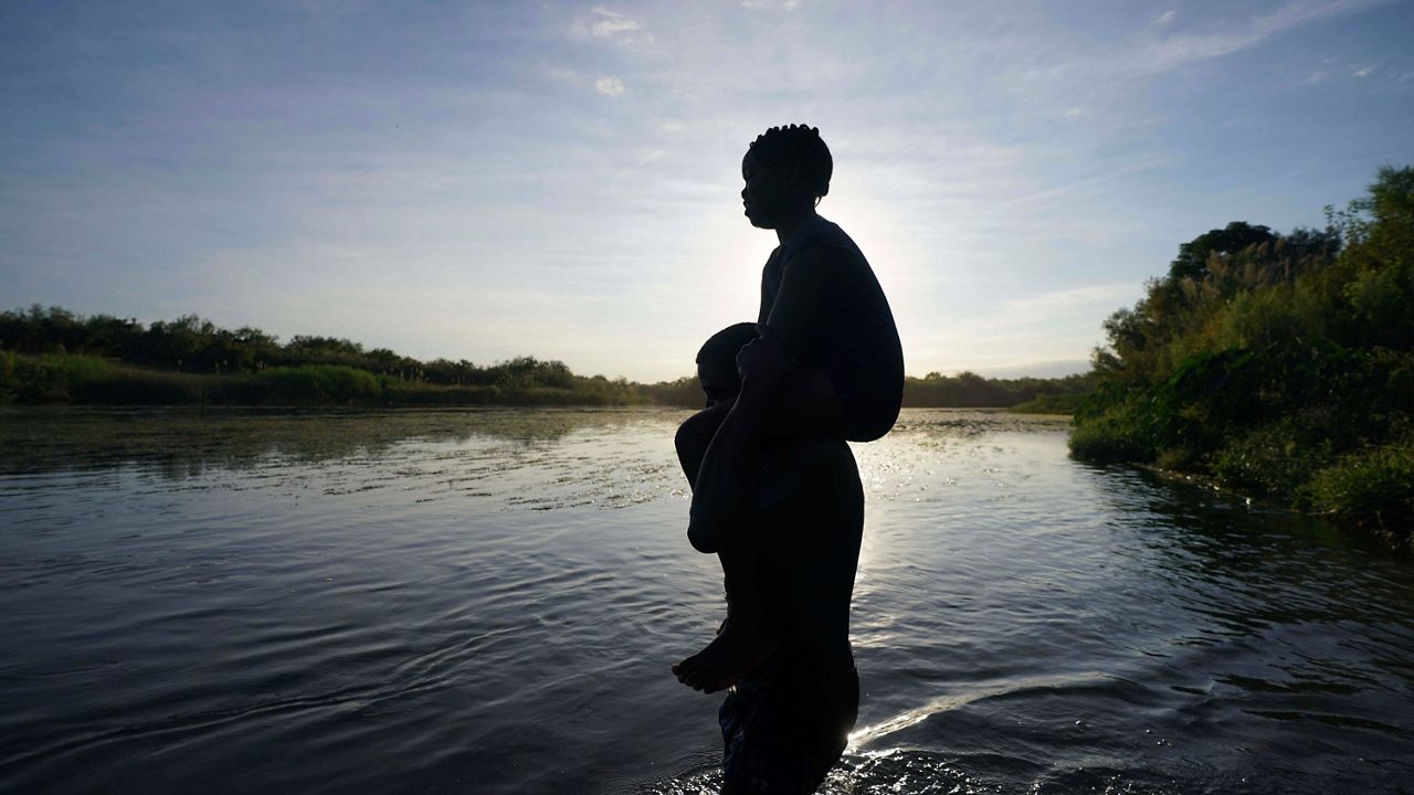 A father carries his daughter over the Rio Grande river toward Del Rio, Texas, from Ciudad Acuna, Mexico, Sept. 22, 2021. A Texas National Guard member who drowned on the U.S.-Mexico border was not wearing a flotation device, and had not been issued one, when he jumped in the Rio Grande to help a migrant who was struggling to swim across, state officials said Wednesday, April 27, 2022. (AP Photo/Fernando Llano, file)