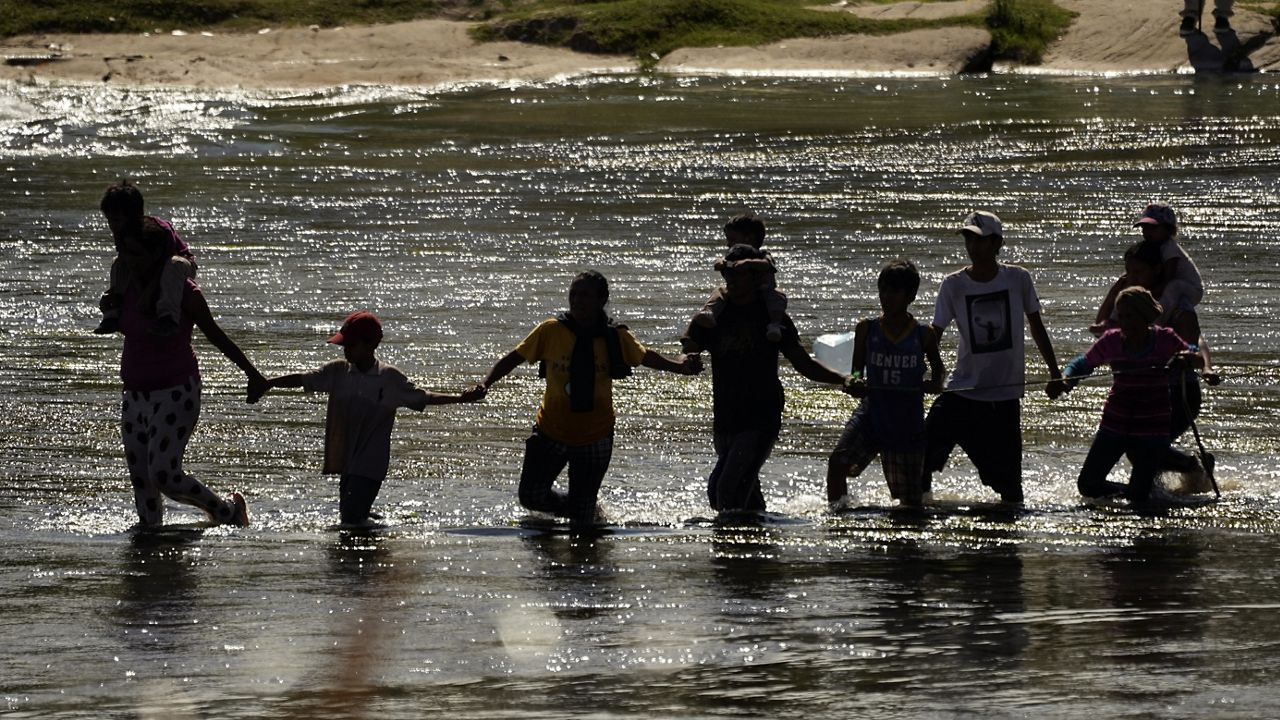 Migrants join hands as they cross the Rio Grande from Mexico into the U.S., Thursday, Sept. 21, 2023, in Eagle Pass, Texas. (AP Photo/Eric Gay)