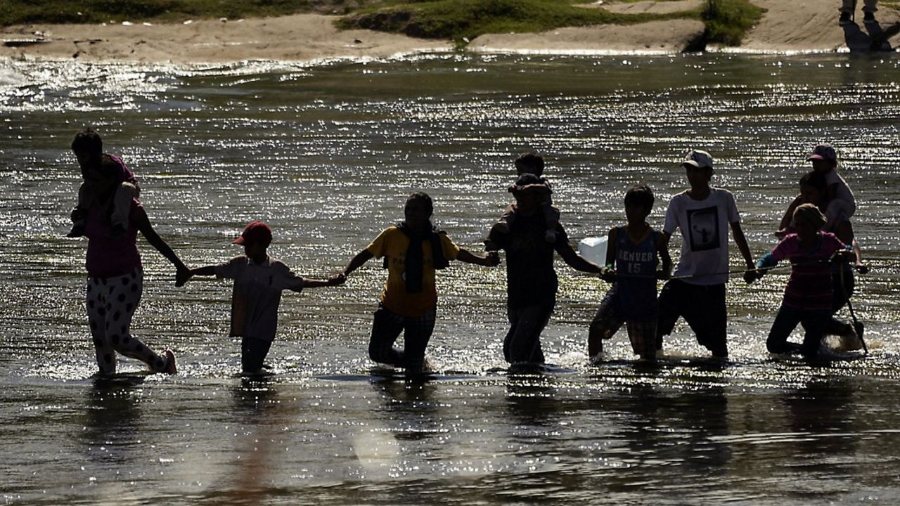 Migrants join hands as they cross the Rio Grande from Mexico into the U.S., Thursday, Sept. 21, 2023, in Eagle Pass, Texas. (AP Photo/Eric Gay)