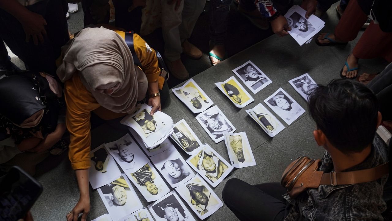 People looking for their family members inspect photographs of soccer riot victims provided by volunteers to help them identify their relatives in Malang, East Java, Indonesia on Sunday, Oct. 2, 2022.