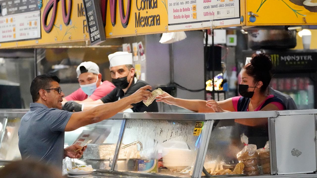 Money is exchanged at a food stand inside Grand Central Market in Los Angeles on July 13. (AP Photo/Marcio Jose Sanchez, File)