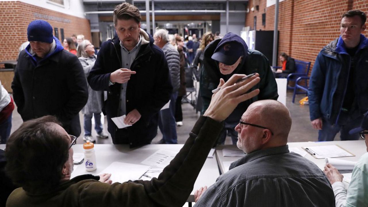 Caucus goers check in at a caucus at Roosevelt High School, Monday, Feb. 3, 2020, in Des Moines, Iowa. (AP Photo/Andrew Harnik)