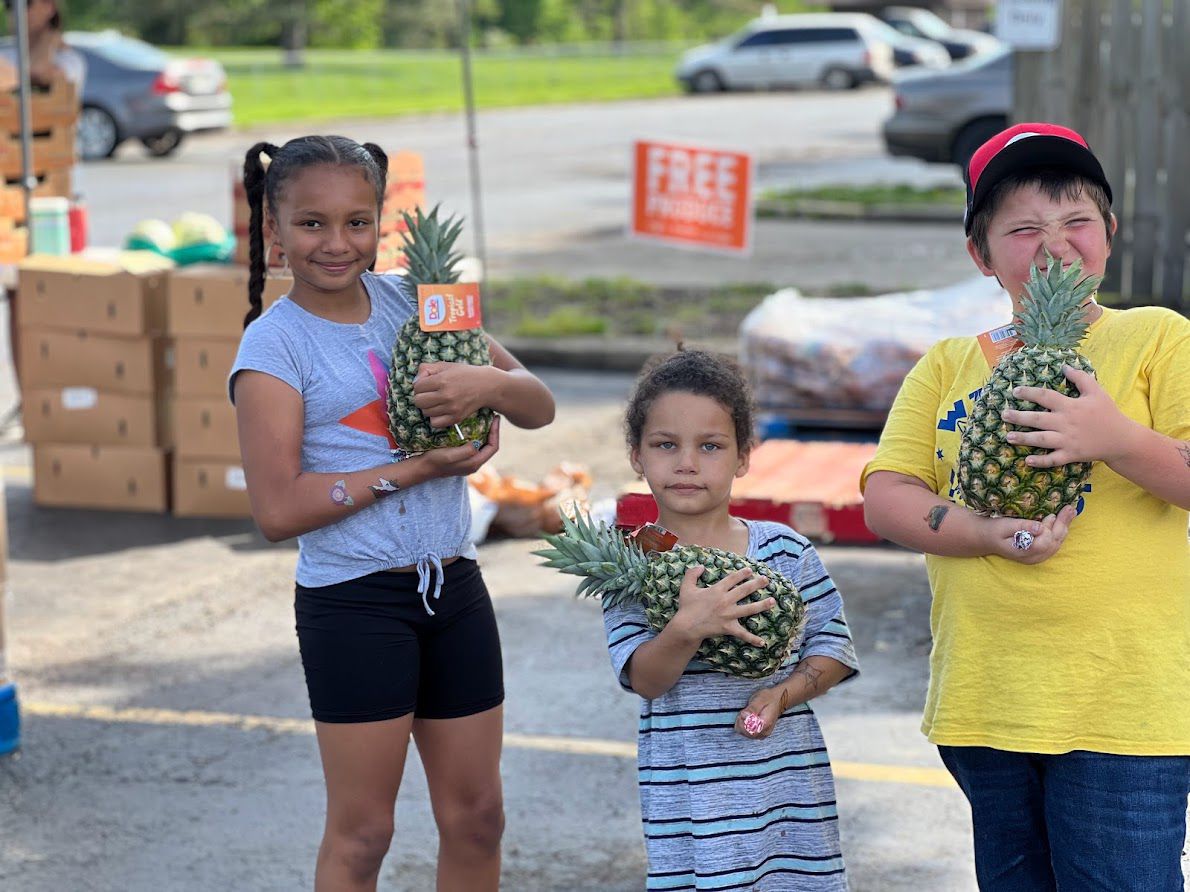 Kids picking up pineapples at an outdoor event hosted by IPM Food Pantry. (Photo courtesy of IPM Food Pantry)