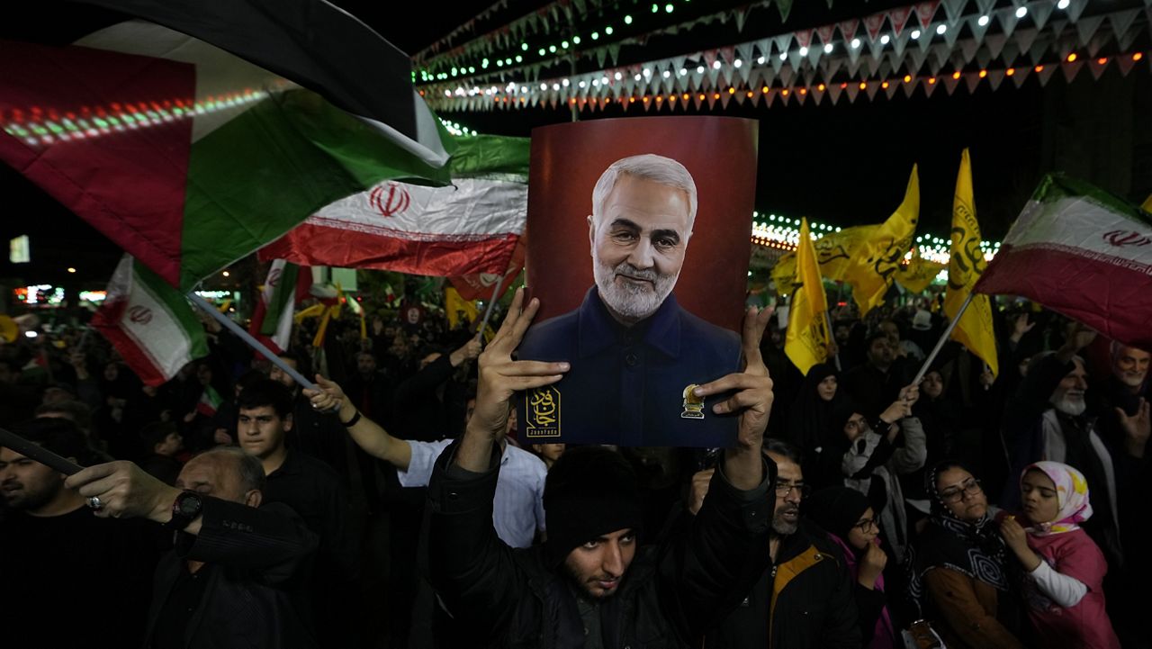 Iranian protesters wave Iranian and Palestinian flags, as one of them holds up a poster of the late Iranian Revolutionary Guard Gen. Qassem Soleimani, during their anti-Israeli gathering to condemn killing members of the Iranian Revolutionary Guards in Syria, in downtown Tehran, Iran, Monday, April 1, 2024. (AP Photo/Vahid Salemi)
