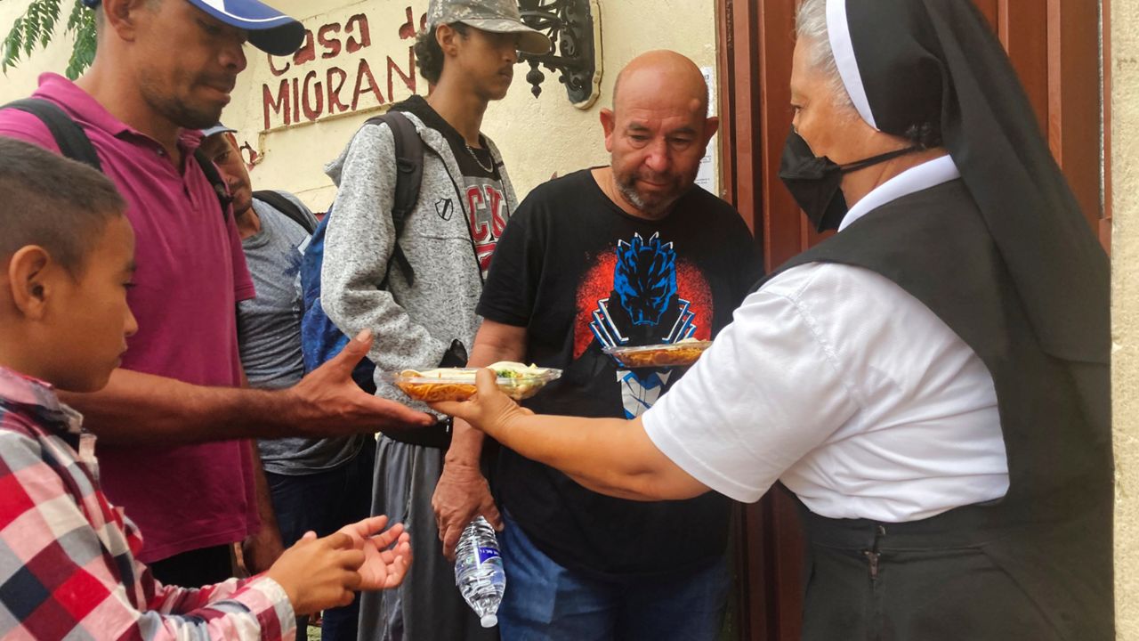 Isabel Turcios, director of the Casa del Migrante migrant services center delivers breakfasts of rice, beans and tortillas to migrants lined up outside, June 1, 2022 in Piedras Negras, Mexico. (AP Photo/Elliot Spagat)