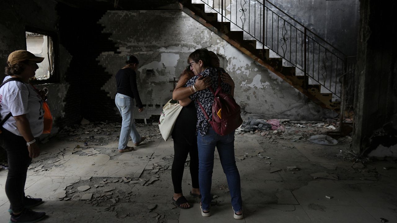 People hug at the house of Maayan and Yuval Bar, killed by Hamas, as Israel marks the one-year anniversary of the Hamas attack on Israel, at the Kibbutz Be'eri, an Israeli communal farm on the Gaza border, on Monday, Oct. 7, 2024. (AP Photo/Ohad Zwigenberg)