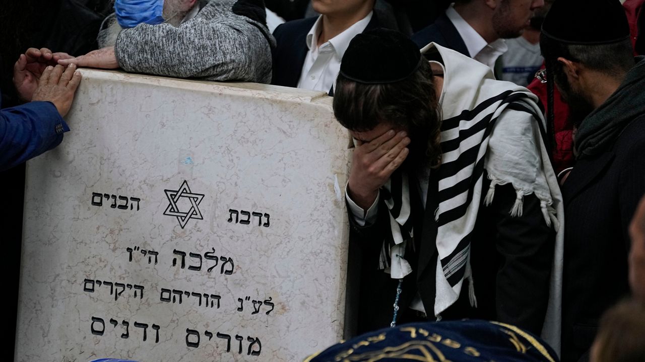 Mourners gather around the bodies of Israeli couple Eli Mizrahi and his wife, Natalie, victims of a shooting attack Friday in east Jerusalem, during their funeral at the cemetery in Beit Shemesh, Israel, early Sunday, Jan. 29, 2023. (AP Photo/Ariel Schalit)