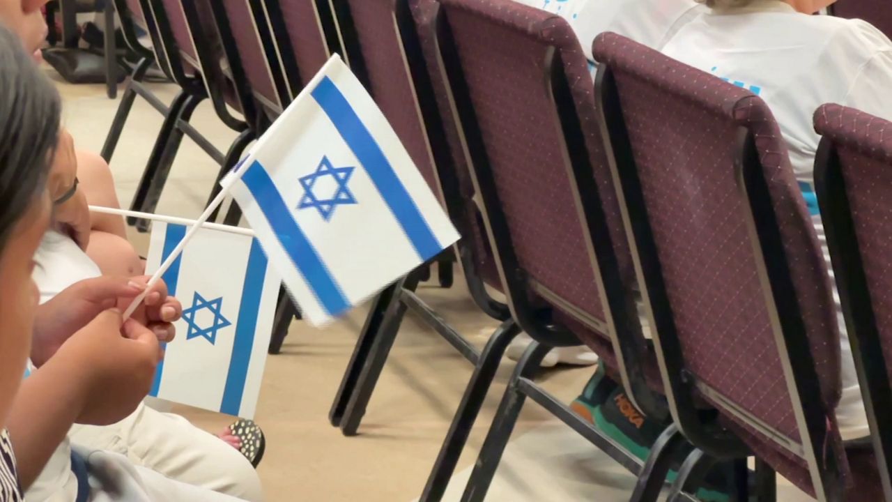 Israeli flags are held during a gathering at Shalom Orlando on Sunday, Oct. 9. 2023. (Spectrum News)