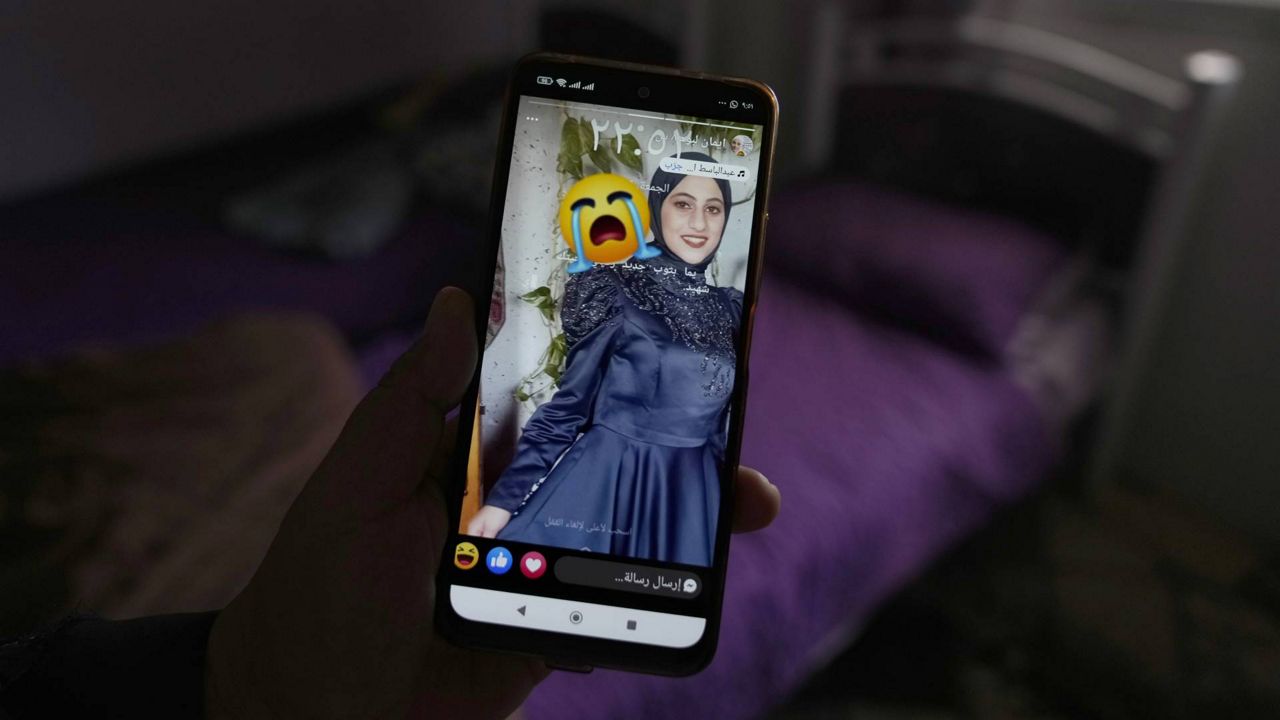 Palestinian Barakat Jabr, 15, displays a photo of his sister Bana Bakr, 13, on his mobile phone in her bedroom at the family house, as he waits for her funeral, in the West Bank village of Qaryut, south of Nablus, Saturday, Sept. 7, 2024. Bakr was killed by Israeli fire the Palestinian health ministry said. The Israeli army said they were reviewing the incident. (AP Photo/Nasser Nasser)