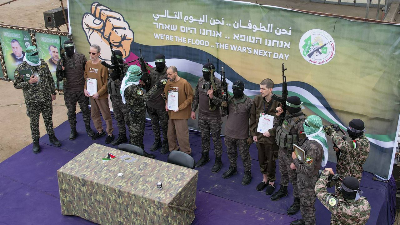 Israeli captives, from left to right, Ohad Ben Ami, Eli Sharabi and Or Levy, who have been held hostage by Hamas in Gaza since October 7, 2023, are escorted by Hamas fighters before being handed over to the Red Cross in Deir al-Balah, central Gaza Strip, Saturday Feb. 8, 2025. (AP Photo/Mohammad Abu Samra)