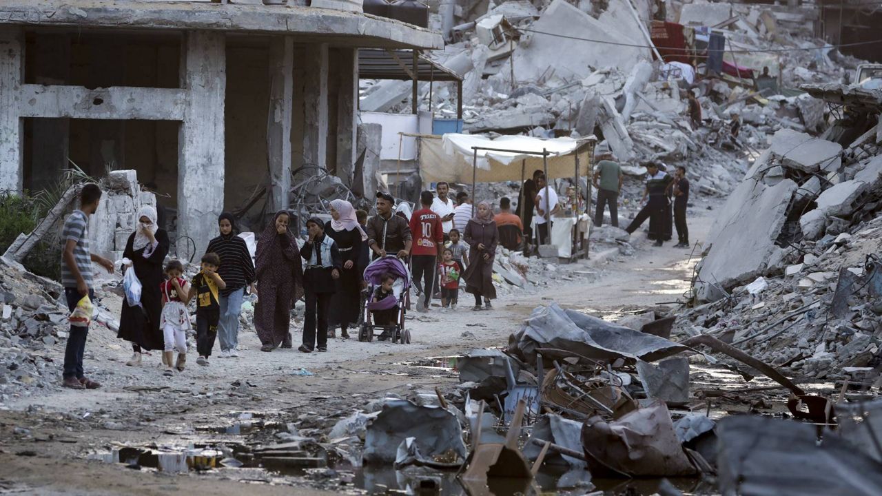 FILE - Palestinians displaced by the Israeli air and ground offensive on the Gaza Strip walk next to sewage flowing into the streets of the southern town of Khan Younis, Gaza Strip, July 4, 2024. Hamas has given initial approval for a U.S.-backed proposal for a phased cease-fire deal in Gaza, dropping a key demand that Israel gives an up-front commitment for a complete end to the war, a Hamas and an Egyptian official said Saturday July 6, 2024. (AP Photo/Jehad Alshrafi, File)