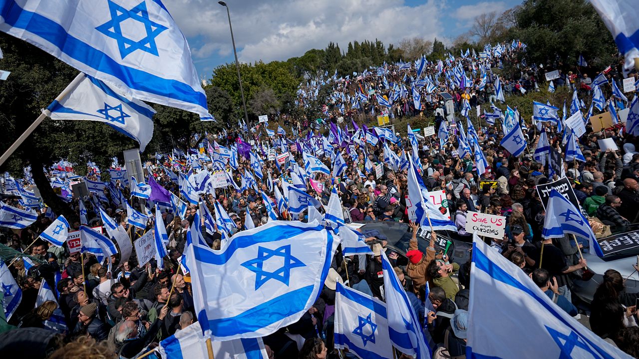 Israelis wave national flags during protest against plans by Prime Minister Benjamin Netanyahu's new government to overhaul the judicial system, outside the Knesset, Israel's parliament, in Jerusalem, Monday, Feb. 13, 2023. Thousands of Israelis protested outside the country's parliament on Monday ahead of a preliminary vote on a bill that would give politicians greater power over appointing judges, part of a judicial overhaul proposed by Prime Minister Benjamin Netanyahu's government. (AP Photo/Ohad Zwigenberg)