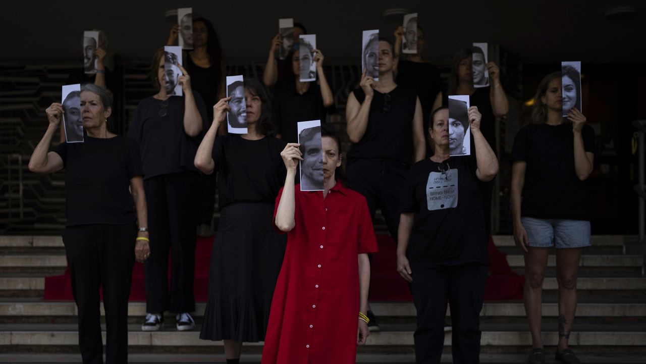Relatives and supporters of Israeli hostages held by Hamas in Gaza hold photos of their loved ones during a performance calling for their return in Tel Aviv, Israel, Thursday, May 23, 2024. (AP Photo/Oded Balilty)