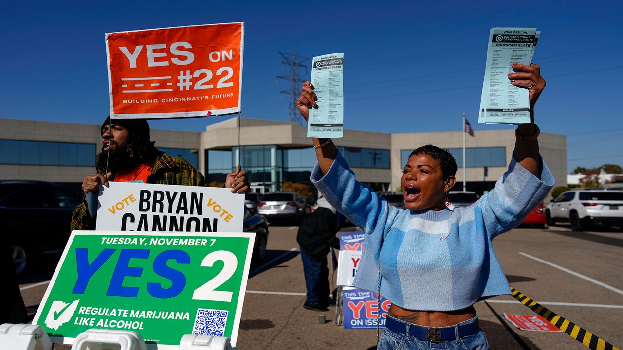 Nikko Griffin, left, and Tyra Patterson, call out to arriving voters in the parking lot of the Hamilton County Board of Elections during early in-person voting in Cincinnati, Thursday, Nov. 2, 2023. They urge people to vote for different issues, including Issue 2, which would allow adult-use sale, purchase, and possession of cannabis for Ohioans who are 21 and older. They also pass out Hamilton County Democratic Party sample ballots. Ohioans will decide next week on whether to legalize recreational marijuana, but people on both sides of the issue say more hangs in the balance than simply decriminalizing the drug. (AP Photo/Carolyn Kaster)