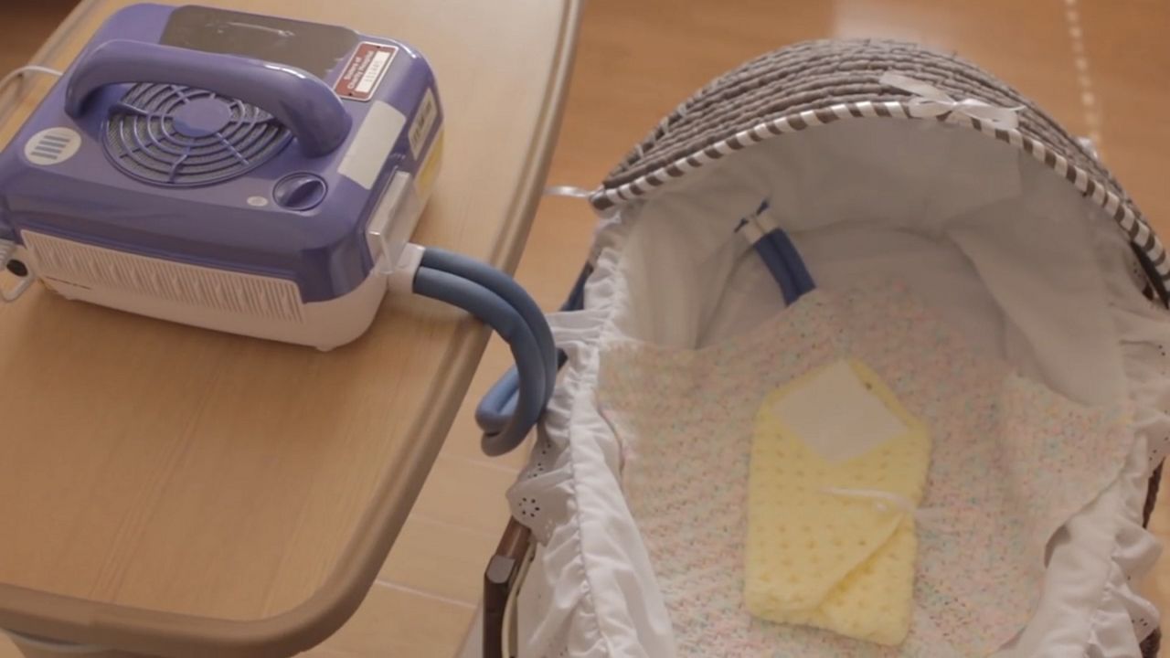 Baby bassinet with blue hose, connected to blue box