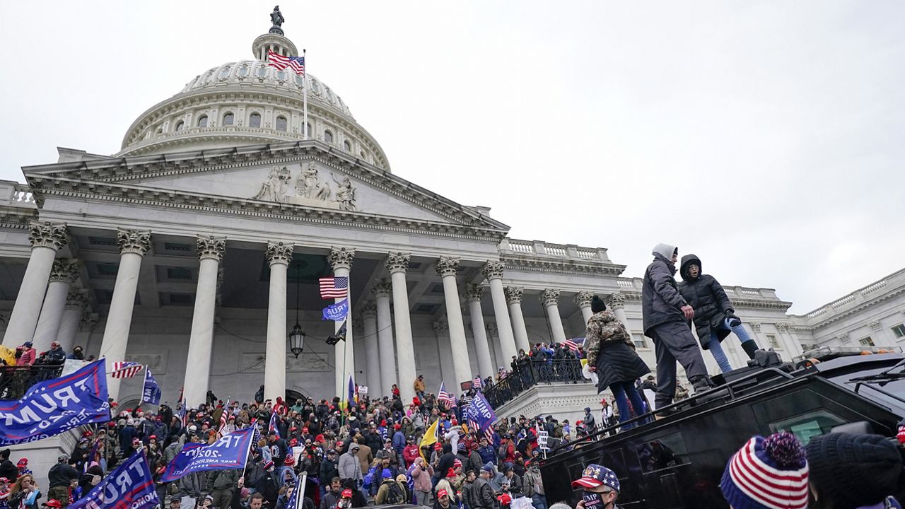 Rioters loyal to President Donald Trump stand on vehicles and the steps of the U.S. Capitol on Jan. 6, 2021, in Washington. (AP Photo/Julio Cortez)