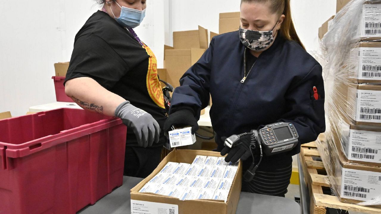 Employees with the McKesson Corporation scan a box of the Johnson & Johnson COVID-19 vaccine while filling an order at their shipping facility in Shepherdsville, Ky., Monday, March 1, 2021. (AP Photo/Timothy D. Easley, Pool)
