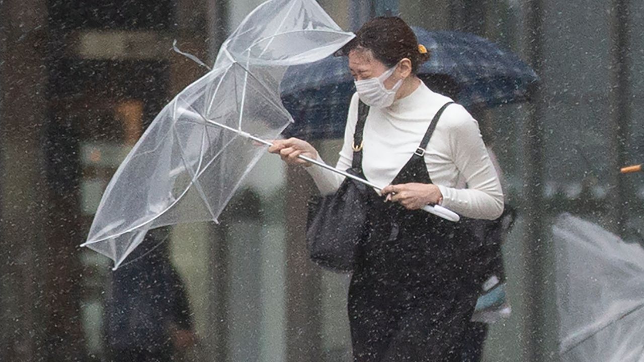 People struggle with rain and strong wind as Typhoon Mindulle travels off the coast of Japan Friday, Oct. 1, 2021, in Tokyo. (AP Photo/Kiichiro Sato)