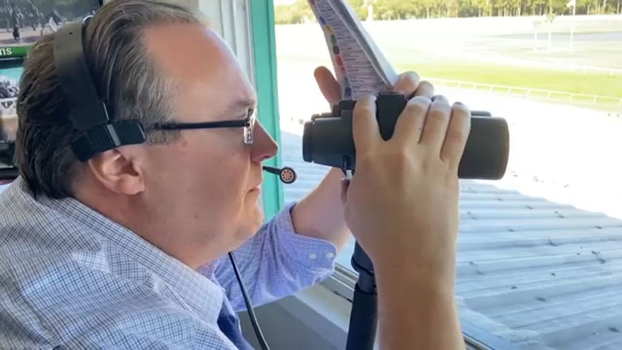 Jason Beem watching the horses race as he announces at Tampa Bay Downs. 