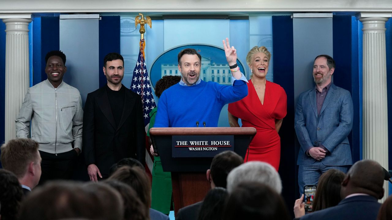 Jason Sudeikis, fourth from left, who plays the title character in the Apple TV+ series “Ted Lasso”, speaks as he joins White House press secretary Karine Jean-Pierre, third from left, and fellow cast members, from left, Toheeb Jimoh, Brett Goldstein, Hannah Waddingham, and Brendan Hunt, during the daily press briefing at the White House in Washington, Monday, March 20, 2023. (AP Photo/Susan Walsh)