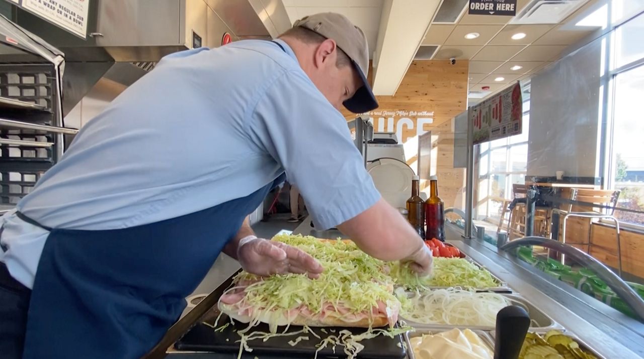 Tim Downing, owner of four local Jersey Mike's, works to make subs for a catering order