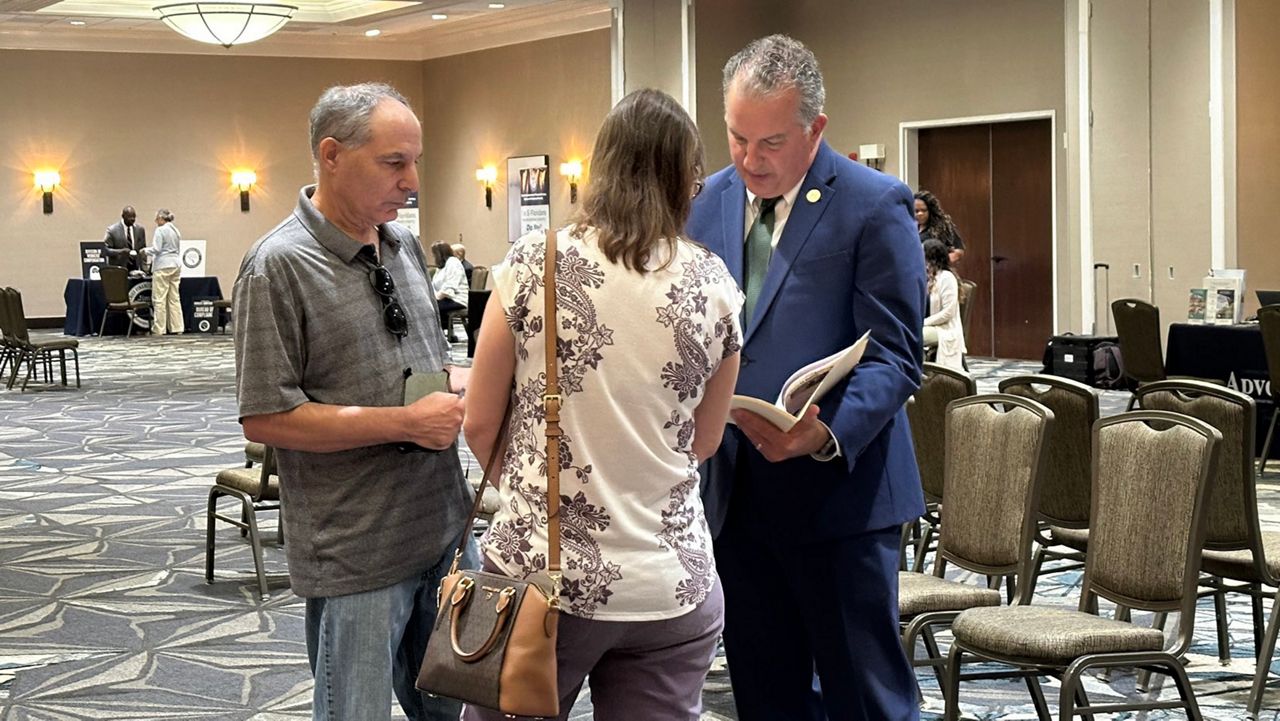 Florida CFO Jimmy Patronis speaks with two people at a "Fixing Problems for Floridians" fair in July 2024. (Massiel Leyva/Spectrum News)