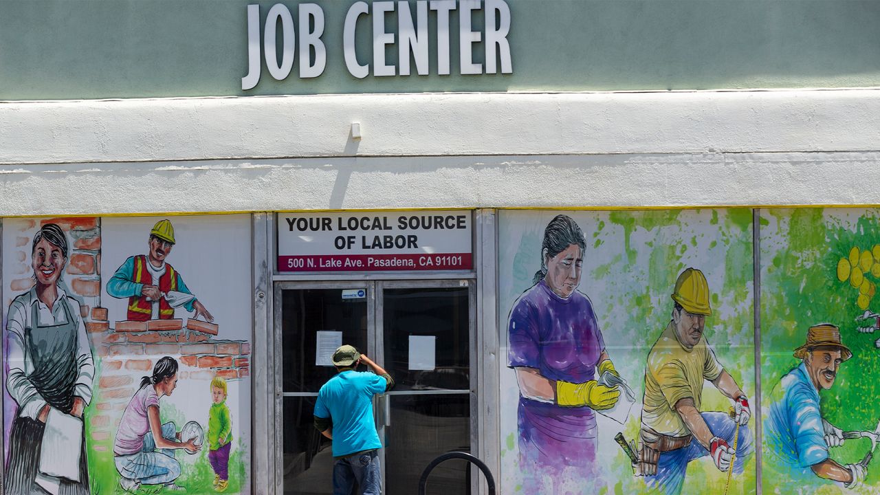 A worker looks inside the closed doors of the Pasadena Community Job Center in Pasadena, Calif., Thursday, May 7, 2020, during the coronavirus outbreak. The center normally connects members of the community, residential customers and small business owners with skilled day laborers. (AP Photo/Damian Dovarganes)