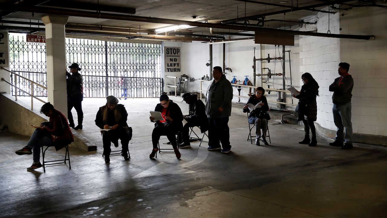 Unionized hospitality workers wait in line in a basement garage to apply for unemployment benefits at the Hospitality Training Academy Friday, March 13, 2020, in Los Angeles. Fearing a widespread health crisis, Californians moved broadly Friday to get in front of the spread of the coronavirus, shuttering schools that educate hundreds of thousands of students, urging the faithful to watch religious services online and postponing or scratching just about any event that could attract a big crowd. (AP Photo/Marcio Jose Sanchez)