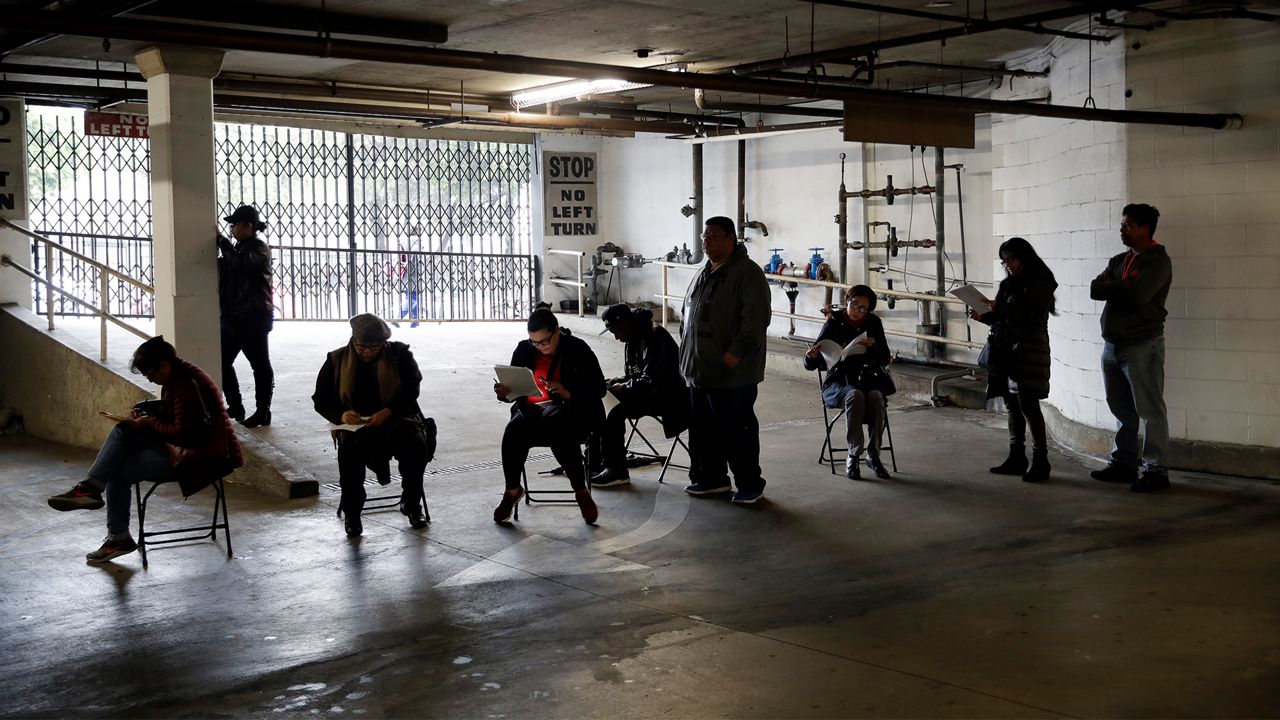 Unionized hospitality workers wait in line in a basement garage to apply for unemployment benefits at the Hospitality Training Academy Friday, March 13, 2020, in Los Angeles. Fearing a widespread health crisis, Californians moved broadly Friday to get in front of the spread of the coronavirus, shuttering schools that educate hundreds of thousands of students, urging the faithful to watch religious services online and postponing or scratching just about any event that could attract a big crowd. (AP Photo/Marcio Jose Sanchez)