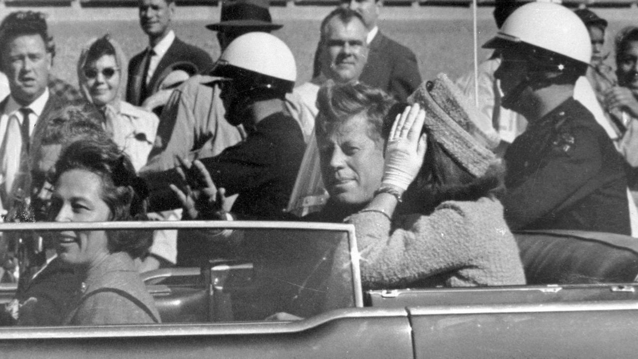 President John F. Kennedy waves from his car in a motorcade approximately one minute before he was shot, Nov. 22, 1963, in Dallas. (AP Photo/Jim Altgens, File)