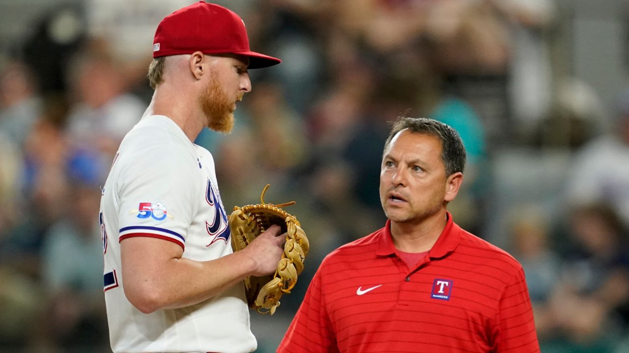Texas Rangers starting pitcher Jon Gray talks with head athletic trainer Matt Lucero, right, in the second inning of a baseball game against the Baltimore Orioles, Monday, Aug. 1, 2022, in Arlington, Texas. Gray left the game with an unknown injury. (AP Photo/Tony Gutierrez)