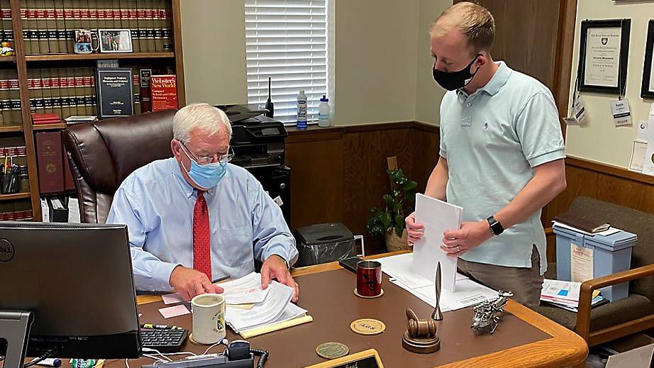 Stonewall County Judge Ronnie Moorhead, left, talks to County Attorney Riley Branch, left, in the judge's office in Aspermont a few days after the rural, west Texas county got its first COVID cases. Moorehead was one of a handful of rural county judges to issue a shelter-in-place order at the state of the pandemic. (Photo by Sabra Ayres/Spectrum News)