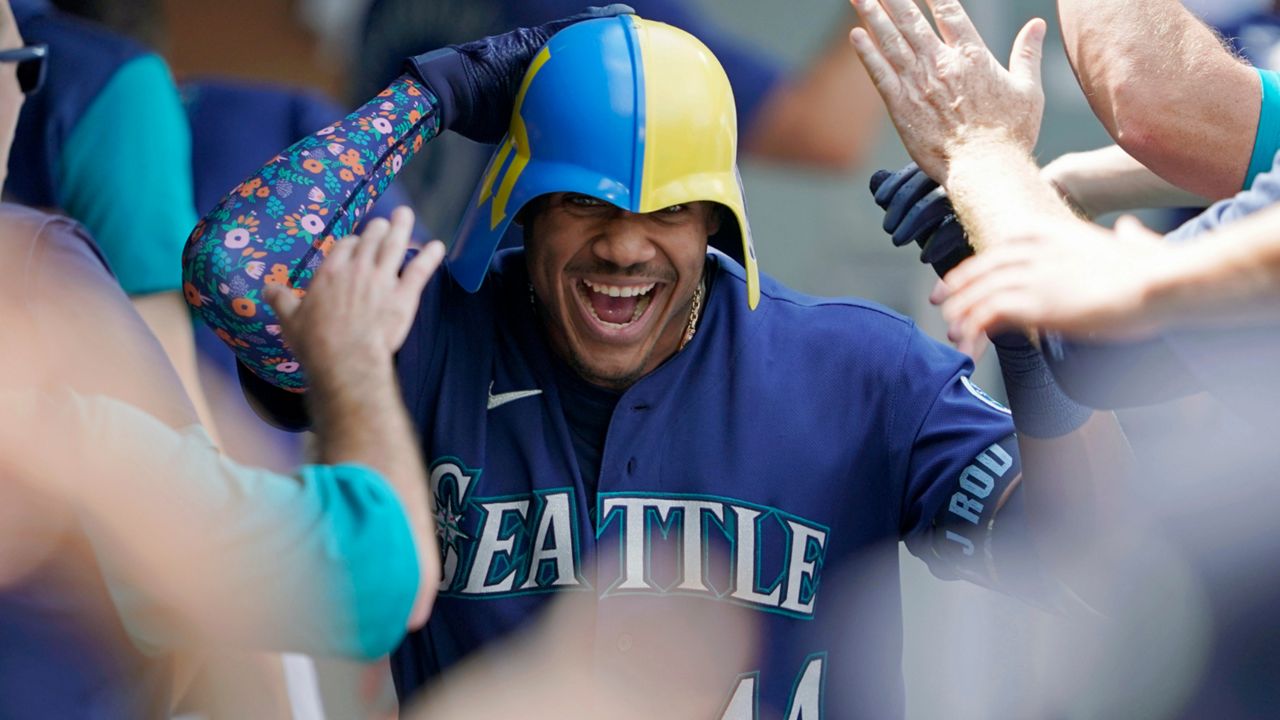 Seattle Mariners' Julio Rodriguez wears a helmet as he is greeted in the dugout after his three-run home run against the Texas Rangers during the seventh inning of a baseball game Wednesday, July 27, 2022, in Seattle. (AP Photo/Ted S. Warren)