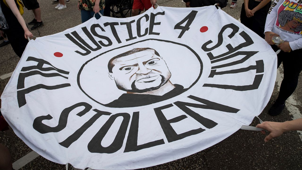 People hold a banner at a rally and march organized by families who were victims of police brutality for the one year anniversary of George Floyd's death on Monday, May 24, 2021, in St. Paul, Minn. (AP Photo/Christian Monterrosa)