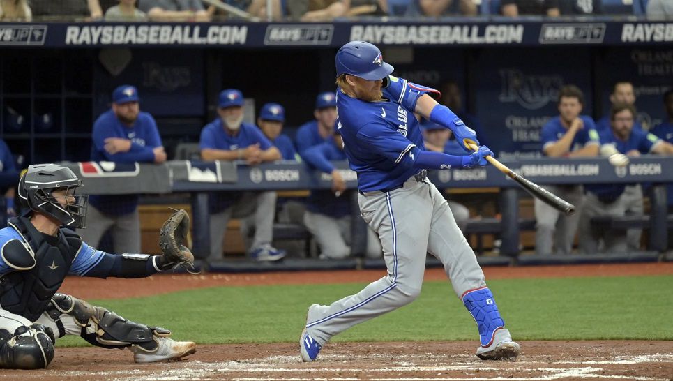 Toronto Blue Jays' Justin Turner hits a two-run double next to Tampa Bay Rays catcher Ben Rortvedt during the second inning of a baseball game Sunday, March 31, 2024, in St. Petersburg, Fla. (AP Photo/Steve Nesius)