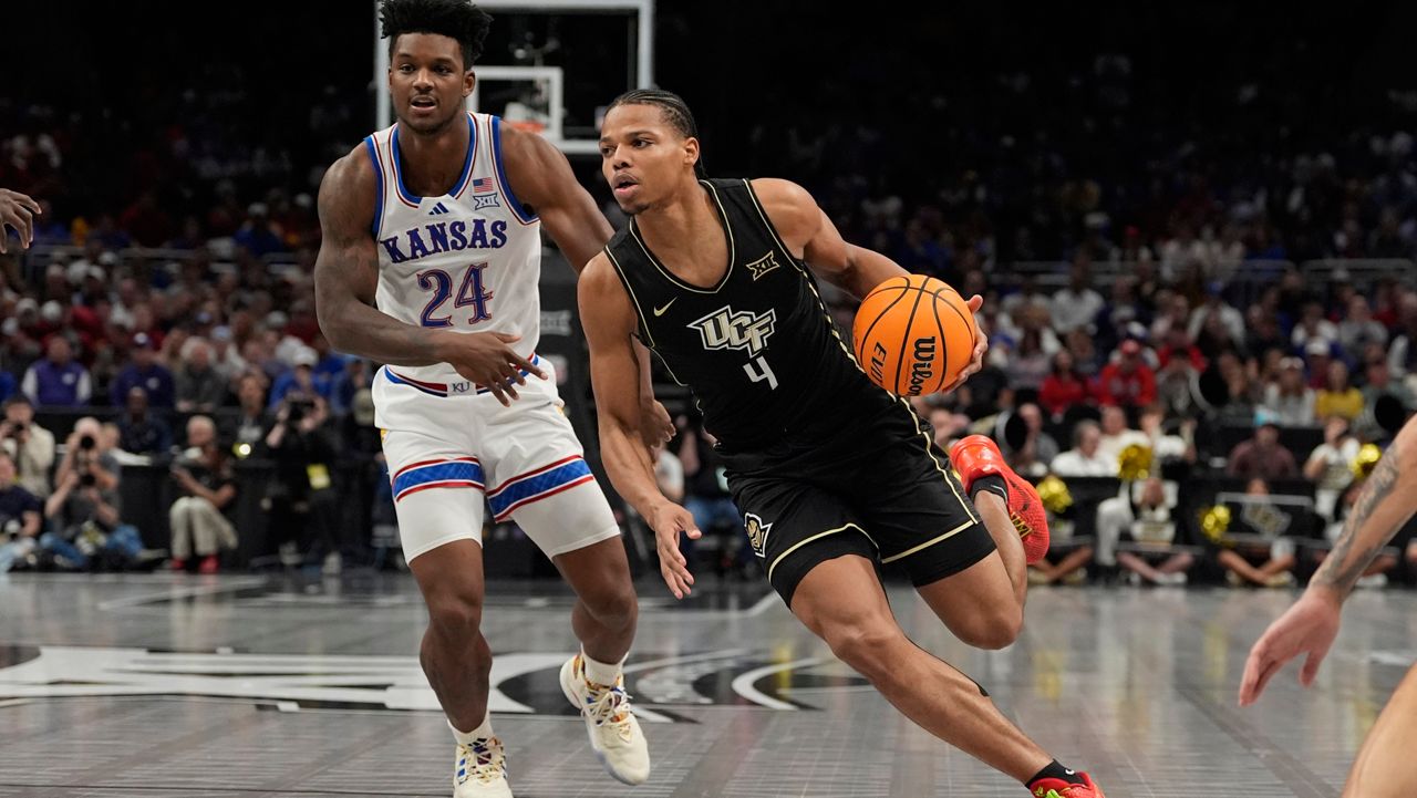 UCF's Keyshawn Hall (4) drives past Kansas's KJ Adams Jr. (24) during the first half of an NCAA college basketball game in the second round of the Big 12 Conference tournament, Wednesday, March 12, 2025, in Kansas City, Mo. (AP Photo/Charlie Riedel)