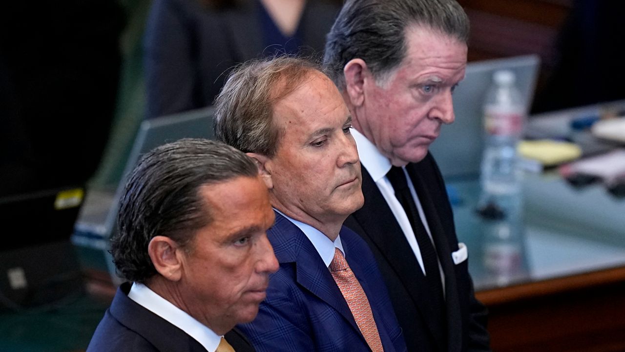 Texas state Attorney General Ken Paxton, center, stands between his attorneys Tony Buzbee, front, and Dan Cogdell, rear, as the articles of his impeachment are read during the his impeachment trial in the Senate Chamber at the Texas Capitol, Tuesday, Sept. 5, 2023, in Austin, Texas. (AP Photo/Eric Gay)