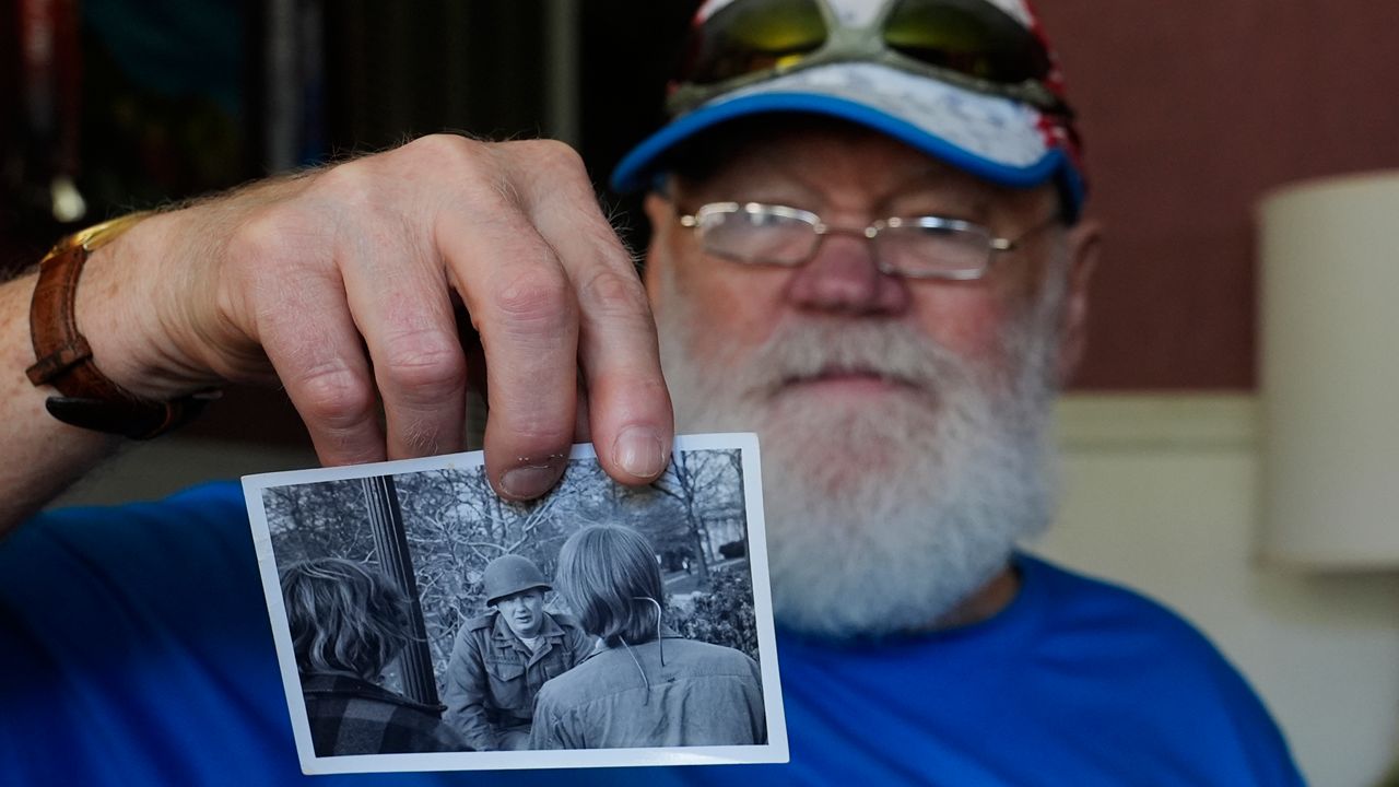 Dean Kahler, who was shot an paralyzed at Kent State University on May 4, 1970, holds a photograph he took of a U.S. National Guardsman talking to students during the 1970 anti-war protest, during an interview in his home Thursday, May 2, 2024, in Plain Township, Ohio. (AP Photo/Sue Ogrocki)