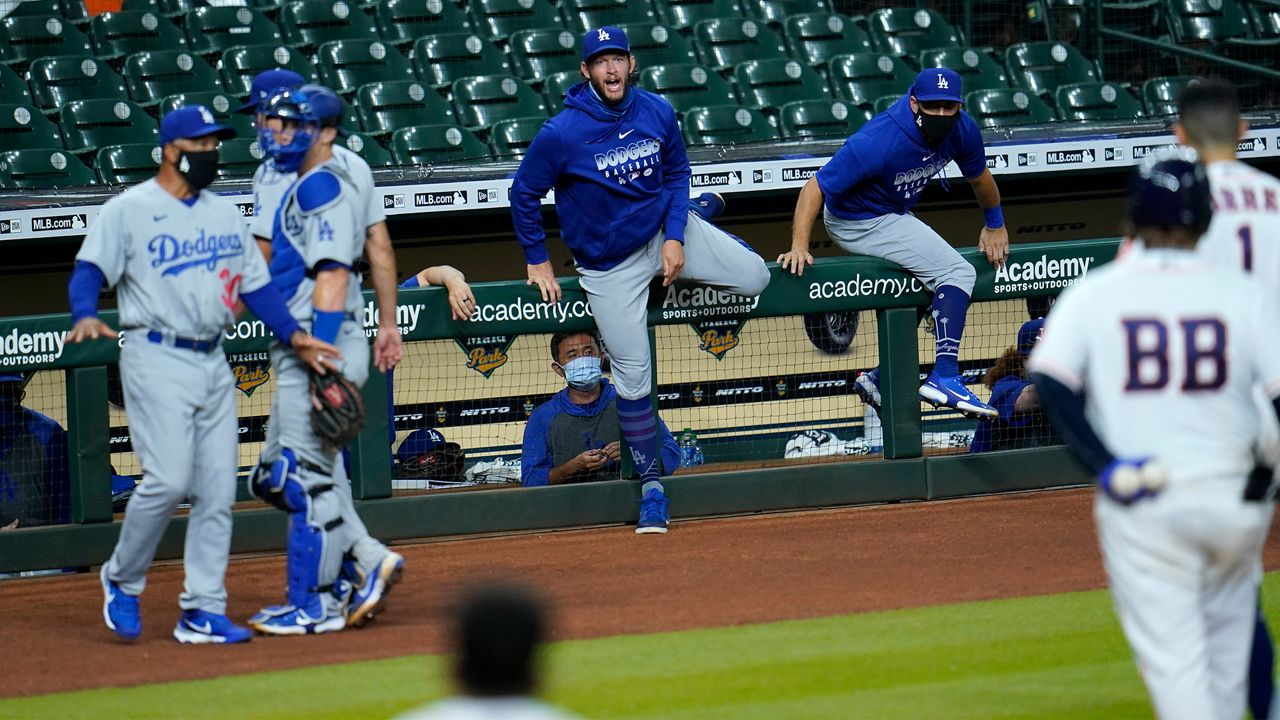 Los Angeles Dodgers' Clayton Kershaw, center, comes over the dugout railing along with other players during an exchange with Houston Astros' Carlos Correa (1) after the sixth inning of a baseball game Tuesday, July 28, 2020, in Houston. Both benches emptied onto the field during the exchange. (AP Photo/David J. Phillip)