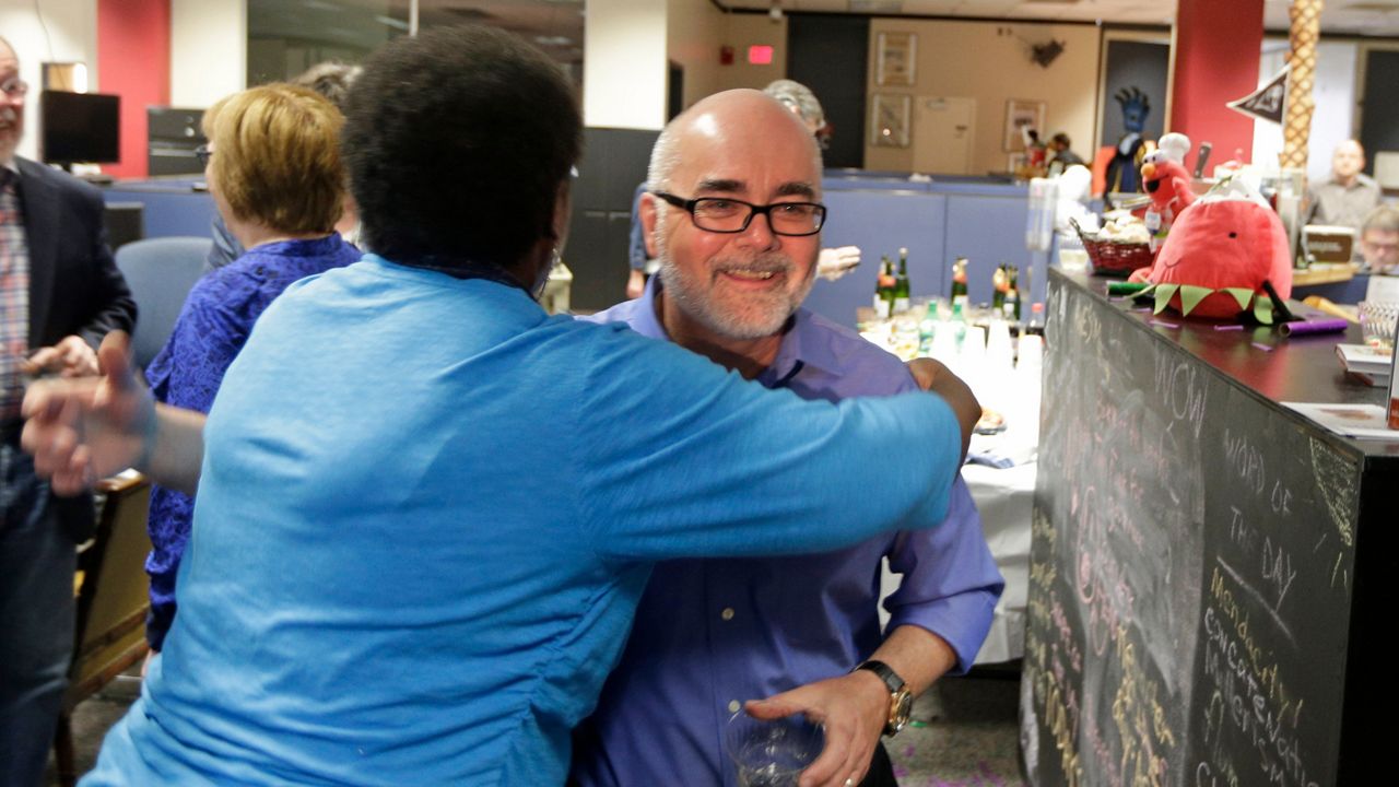 Charlotte Observer editorial cartoonist Kevin Siers, right, gets a hug from a co-worker in the newsroom to celebrate Siers winning the Pulitzer Prize for Editorial Cartooning at the newspaper in Charlotte, N.C., on Monday, April 14, 2014. (AP file photo/Chuck Burton)